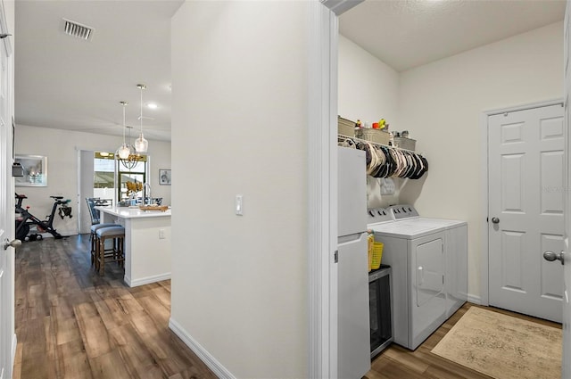 laundry room with washer and dryer, wood finished floors, laundry area, visible vents, and baseboards