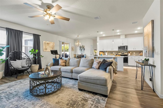 living area featuring a ceiling fan, light wood-type flooring, and visible vents