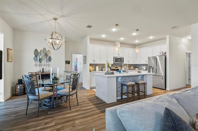 interior space featuring an inviting chandelier, stainless steel appliances, wood finished floors, and open floor plan
