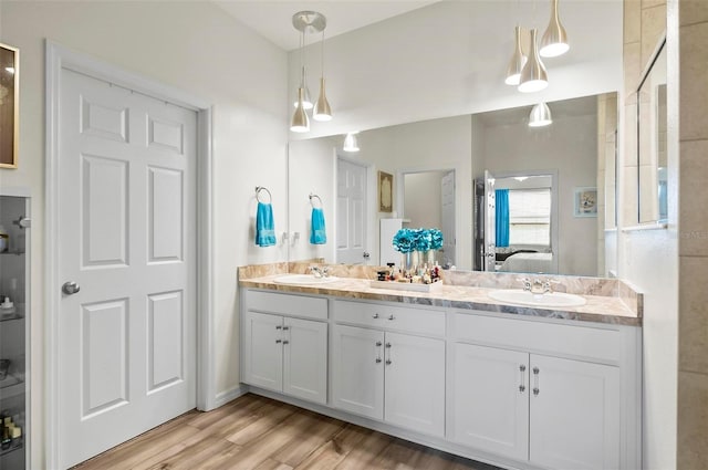 bathroom with double vanity, connected bathroom, wood finished floors, and a sink