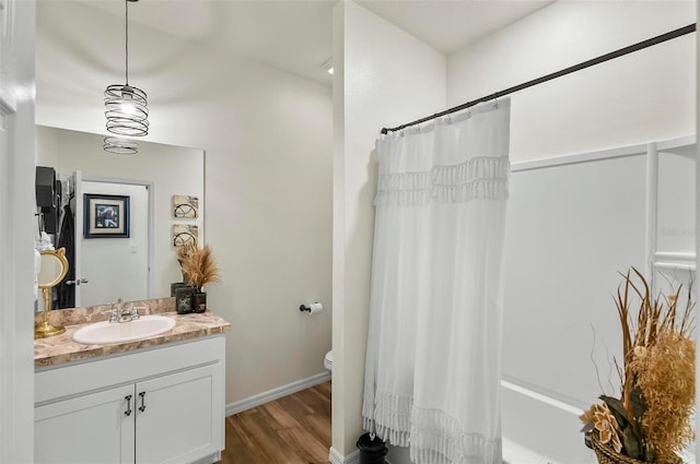 bathroom with toilet, wood finished floors, shower / bath combo, baseboards, and vanity