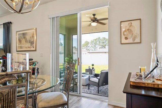 dining area featuring wood finished floors and ceiling fan with notable chandelier