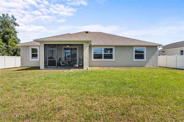 rear view of property featuring a lawn, a sunroom, and a fenced backyard