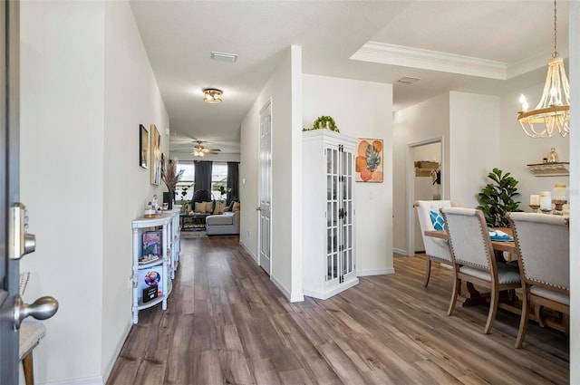 interior space with visible vents, baseboards, dark wood-type flooring, a chandelier, and ornamental molding