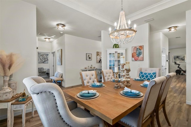 dining area featuring light wood finished floors, crown molding, visible vents, and a notable chandelier