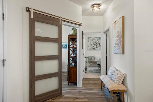 hallway with a barn door and wood finished floors