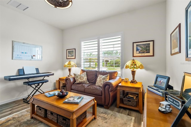 living room with baseboards, visible vents, and wood finished floors