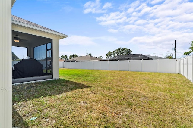 view of yard featuring a fenced backyard, a sunroom, and a ceiling fan