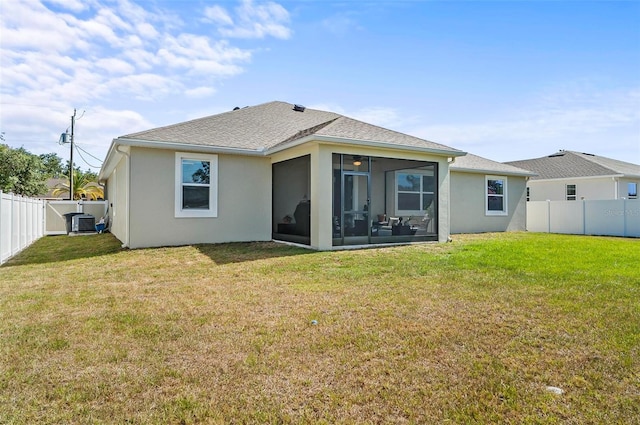 rear view of house featuring a fenced backyard, a sunroom, stucco siding, and a lawn
