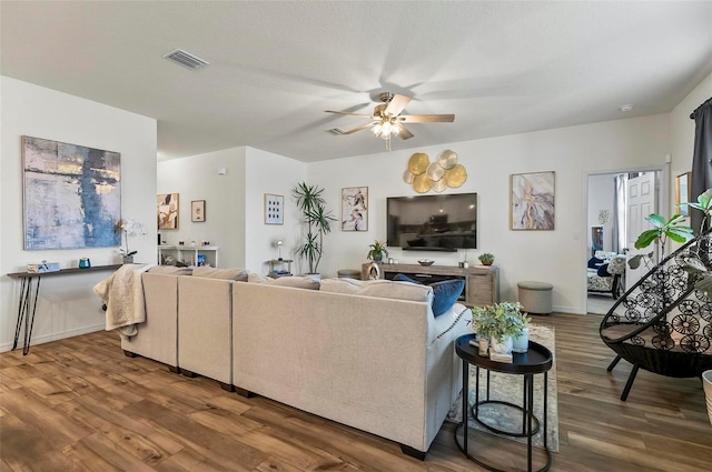 living room with a ceiling fan, baseboards, visible vents, and wood finished floors