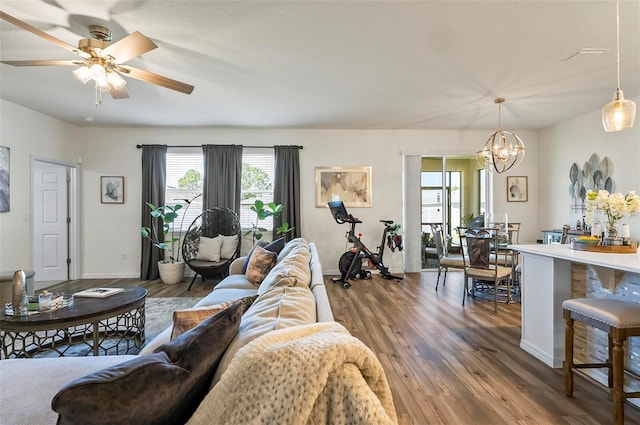living area with ceiling fan with notable chandelier, baseboards, and wood finished floors