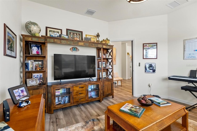 living room featuring visible vents, wood finished floors, and baseboards