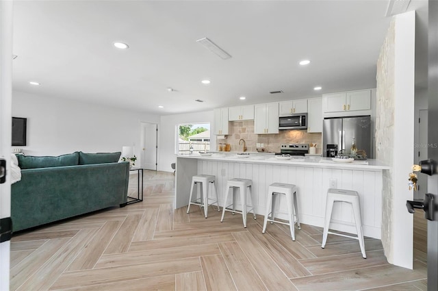 104 Foxhall Ln, Palm Coast, FL 32137 - kitchen with appliances with stainless steel finishes, a kitchen bar, white cabinets, light countertops, and recessed lighting