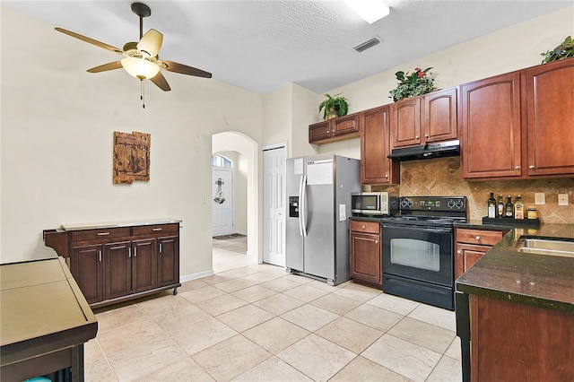 237 N Hidden Tree Dr, Saint Augustine, FL 32086 - kitchen with appliances with stainless steel finishes, dark countertops, under cabinet range hood, arched walkways, and backsplash