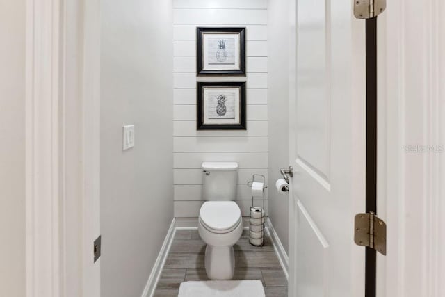 bathroom with baseboards, toilet, and wood finished floors