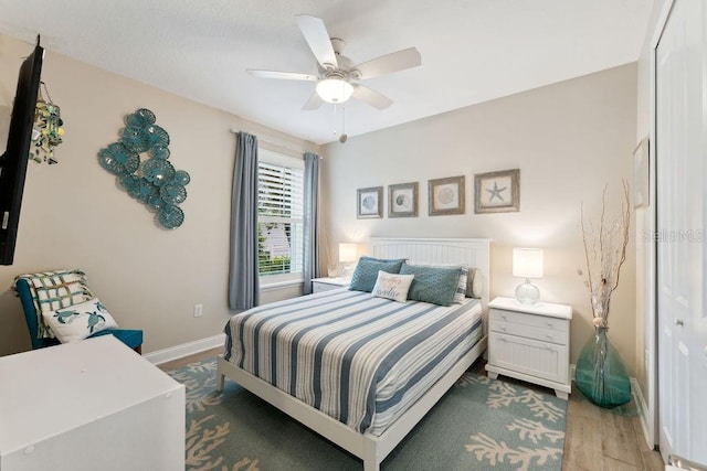 bedroom with baseboards, wood finished floors, and a ceiling fan