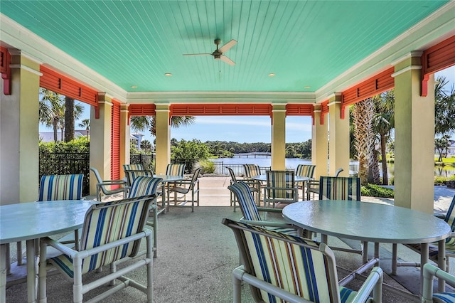 view of patio with outdoor dining space, a water view, and ceiling fan