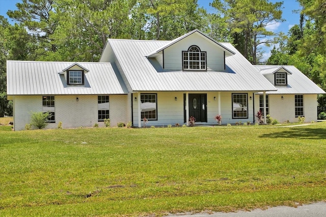 view of front facade featuring a front lawn, brick siding, covered porch, and metal roof