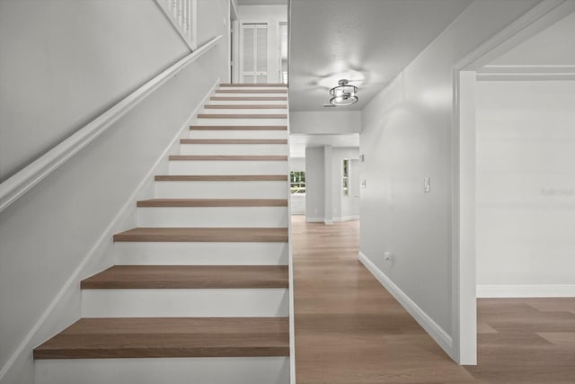 staircase featuring baseboards and wood finished floors