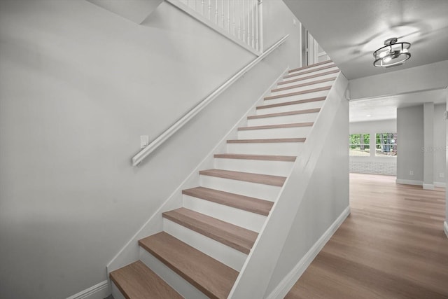 staircase featuring baseboards and wood finished floors