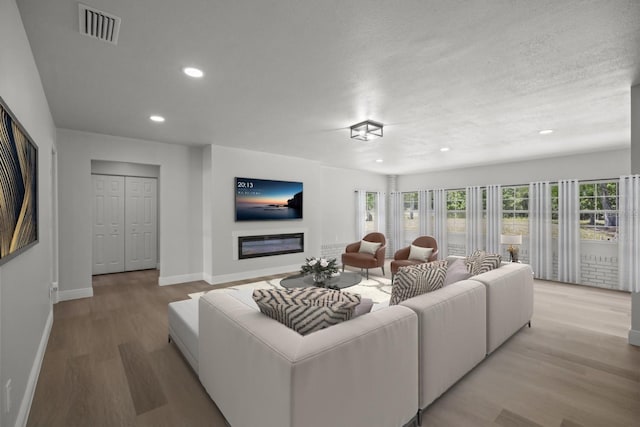 living area with recessed lighting, baseboards, visible vents, and light wood-style floors