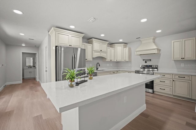 kitchen with light countertops, a sink, appliances with stainless steel finishes, and custom range hood