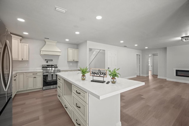 kitchen featuring stainless steel appliances, open floor plan, light countertops, a kitchen island, and custom range hood