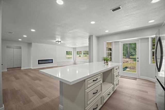 kitchen featuring light wood-type flooring, light countertops, baseboards, and visible vents