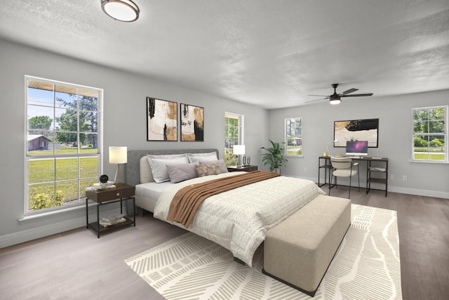 bedroom featuring a textured ceiling, baseboards, a ceiling fan, and wood finished floors