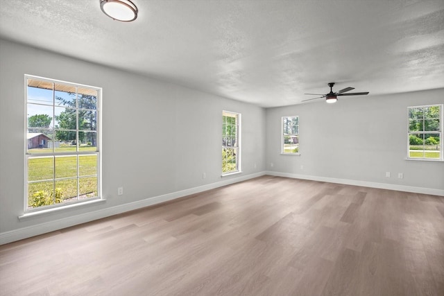 unfurnished room featuring baseboards, ceiling fan, a textured ceiling, and wood finished floors
