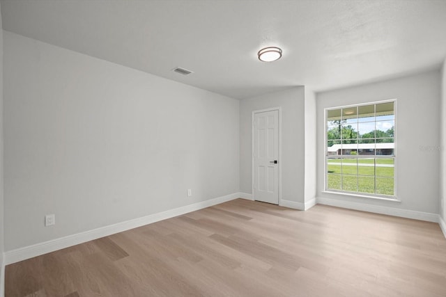 empty room with visible vents, light wood-style flooring, and baseboards