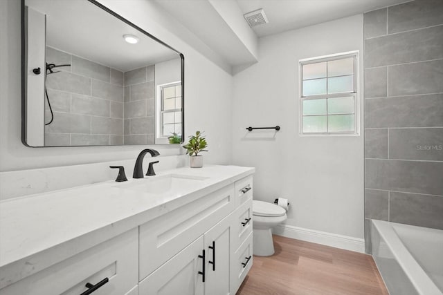 full bathroom with toilet, baseboards, visible vents, vanity, and wood finished floors