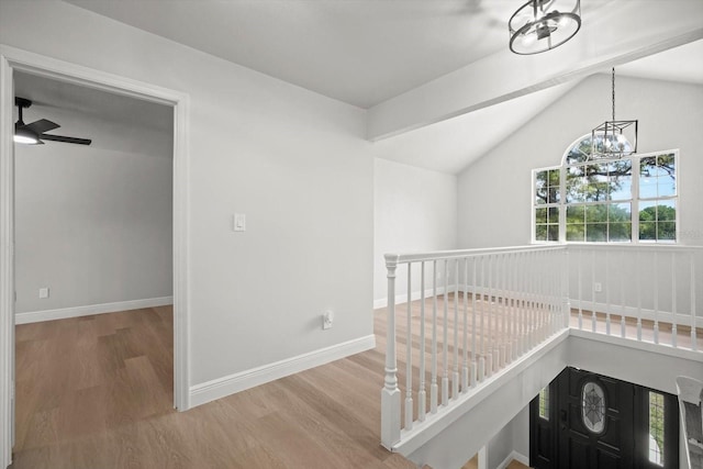 hallway with lofted ceiling, baseboards, a chandelier, wood finished floors, and an upstairs landing