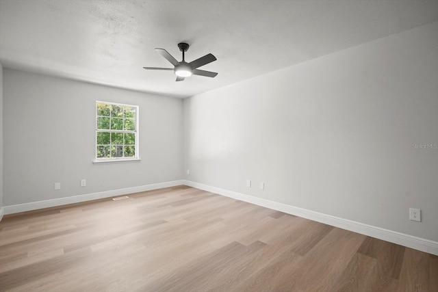spare room with visible vents, light wood-style flooring, baseboards, and ceiling fan