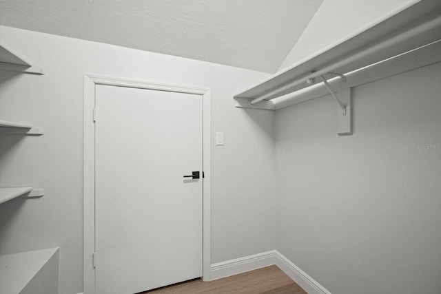 spacious closet with lofted ceiling and wood finished floors