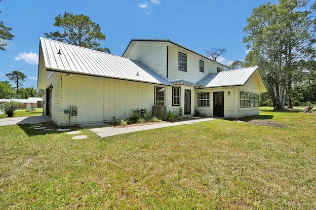 rear view of property with a lawn, metal roof, and a standing seam roof
