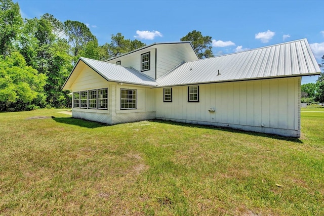 rear view of property featuring metal roof and a lawn