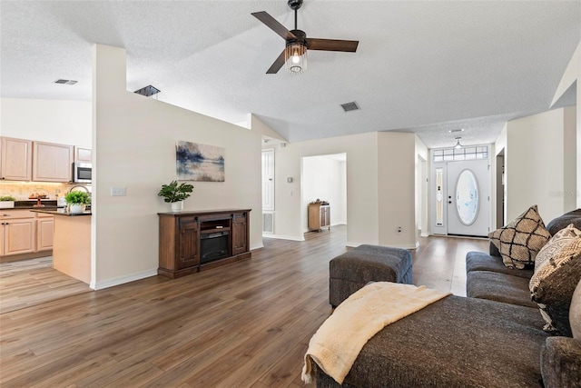 49 Louisiana Dr, Palm Coast, FL 32137 - living area featuring light wood-style flooring, lofted ceiling, ceiling fan, baseboards, and a textured ceiling
