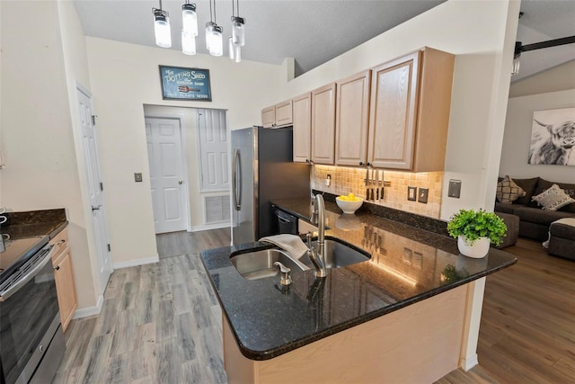 49 Louisiana Dr, Palm Coast, FL 32137 - kitchen featuring decorative backsplash, light brown cabinetry, stainless steel appliances, dark stone countertops, and light wood-style floors