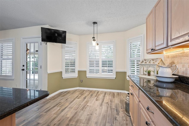 49 Louisiana Dr, Palm Coast, FL 32137 - kitchen featuring light wood-type flooring, a textured ceiling, dark stone countertops, decorative backsplash, and baseboards