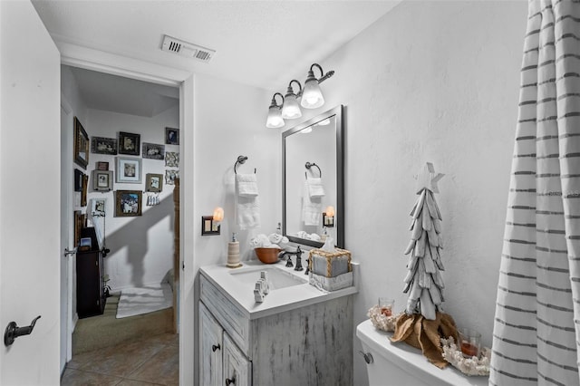 1601 N Ocean Shore Blvd, Flagler Beach, FL 32136 - full bath with tile patterned floors, toilet, vanity, and a textured ceiling