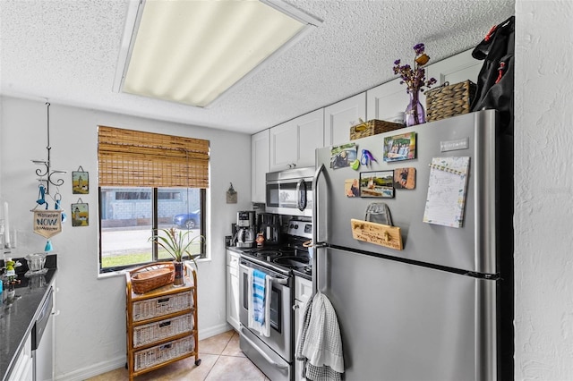 1601 N Ocean Shore Blvd, Flagler Beach, FL 32136 - kitchen with stainless steel appliances, white cabinetry, light tile patterned floors, a textured ceiling, and dark countertops