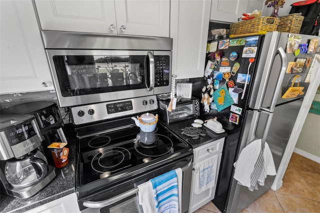 1601 N Ocean Shore Blvd, Flagler Beach, FL 32136 - kitchen with stainless steel appliances, white cabinets, dark countertops, and light tile patterned floors