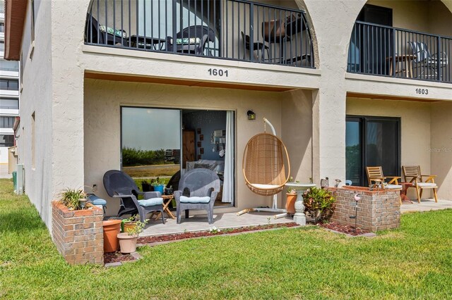 1601 N Ocean Shore Blvd, Flagler Beach, FL 32136 - doorway to property with stucco siding, a balcony, and a lawn