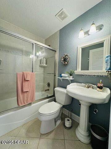 3000 Ocean Shore Blvd Unit 150, Ormond Beach, FL 32176 - full bath with toilet, a textured ceiling, visible vents, tile patterned floors, and combined bath / shower with glass door