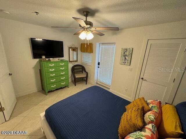3000 Ocean Shore Blvd Unit 150, Ormond Beach, FL 32176 - bedroom featuring light tile patterned floors, baseboards, a ceiling fan, and a textured ceiling