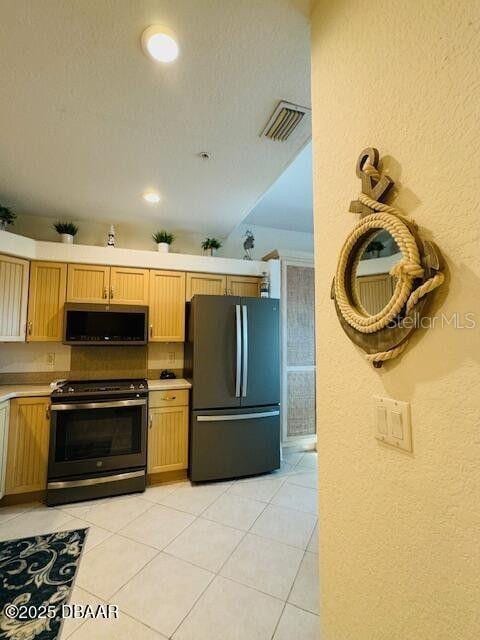 3000 Ocean Shore Blvd Unit 150, Ormond Beach, FL 32176 - kitchen featuring stainless steel microwave, freestanding refrigerator, visible vents, a textured wall, and electric range oven