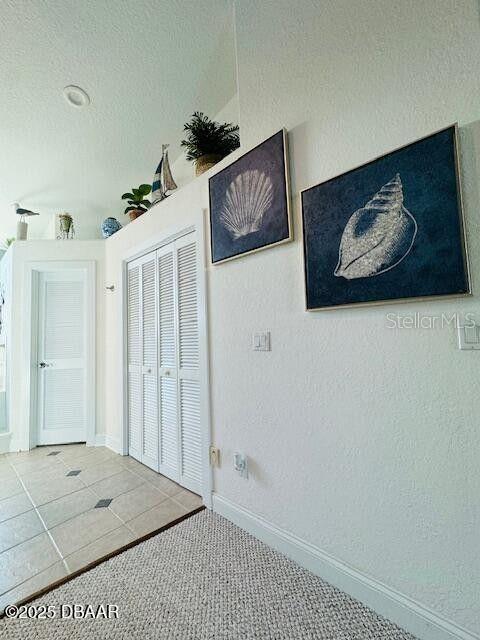 3000 Ocean Shore Blvd Unit 150, Ormond Beach, FL 32176 - unfurnished bedroom with carpet flooring, a closet, baseboards, and tile patterned flooring