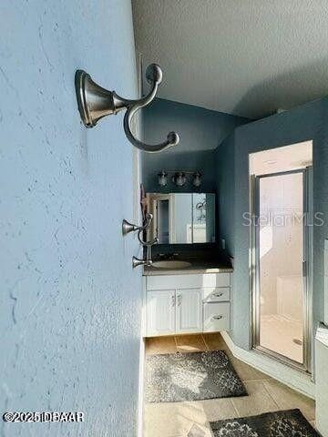 3000 Ocean Shore Blvd Unit 150, Ormond Beach, FL 32176 - bathroom with vanity, a textured ceiling, a shower stall, and tile patterned flooring