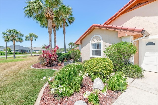 22 San Carlos Dr, Palm Coast, FL 32137 - view of home's exterior with stucco siding, a lawn, a tiled roof, and an attached garage